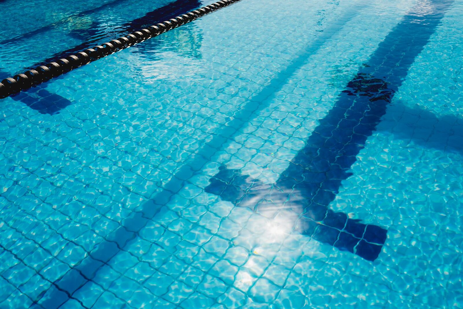 Clear pool water over blue tiles with a lane line